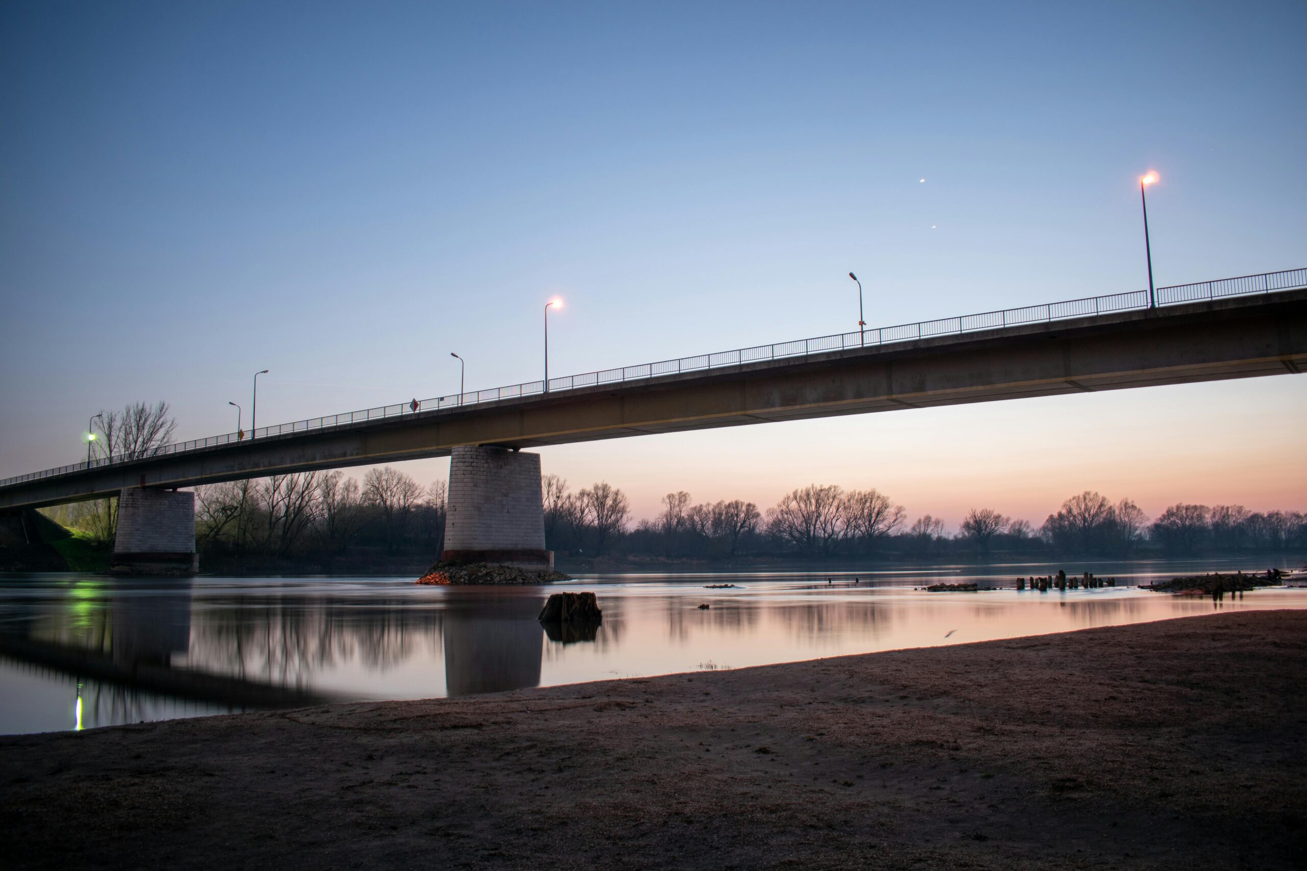 A serene bridge scene at twilight over a calm river in Barcs, Hungary.